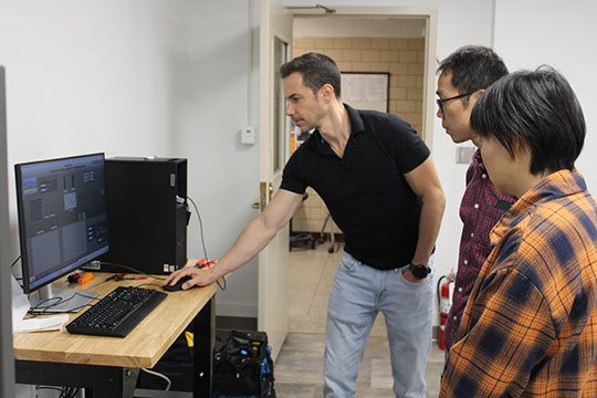 A professor demonstrates a computer program to two students in a lab at Alfred University.