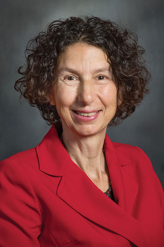 headshot of woman with curly black hair, smiling