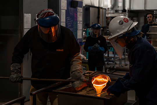 two people working with molten glass