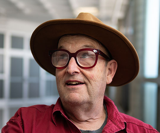 headshot of man with hat and glasses