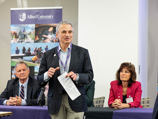 Man talking with two people at table in background