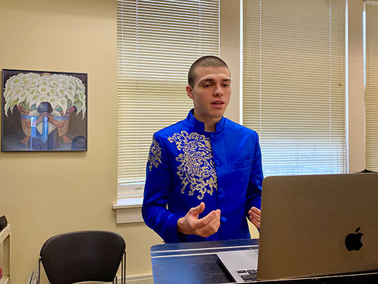 man standing in front of a laptop, talking