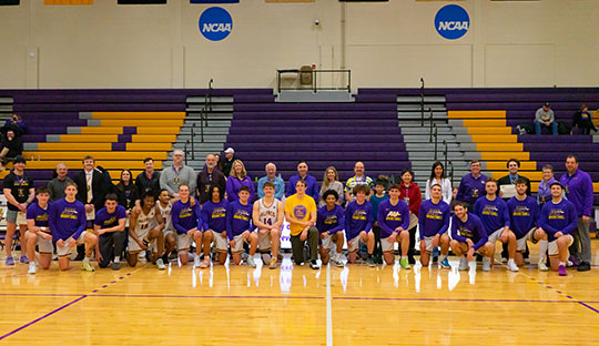 group of men's basketball players pictured with a row of faculty and staff