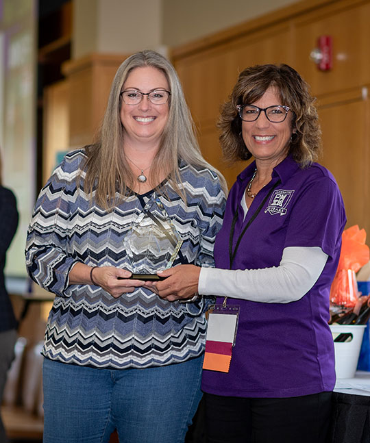 woman presenting a trophy to another woman