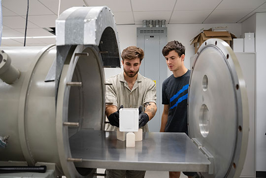 two men standing by research equipment