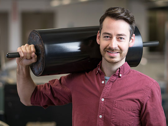 headshot of man in button down shirt holding a print ink roller