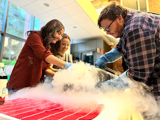 man and two women conducting a demonstration with liquid nitrogen
