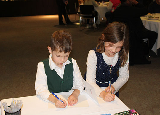 two children writing on cards