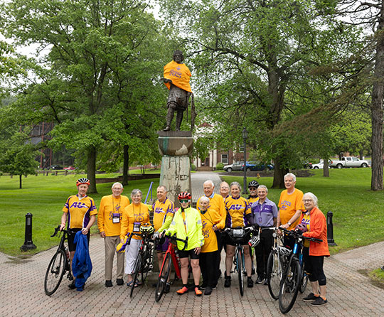 several people with bicycles posed in front of a statue