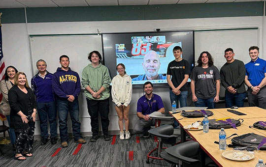 group of people standing in front of a video screen