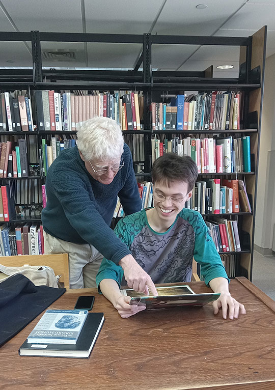 two people looking over a book in a library
