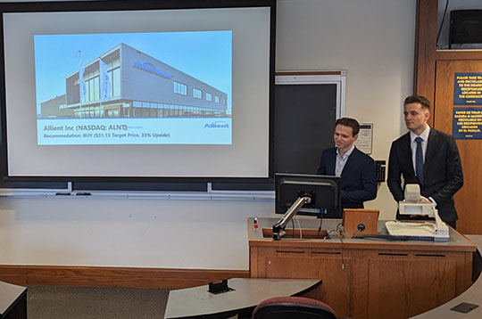 two young men in front of video screen making presentation
