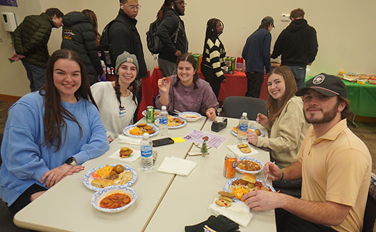 Group of Alfred University students sitting together and enjoying a meal during the College of Business Finals Feast.