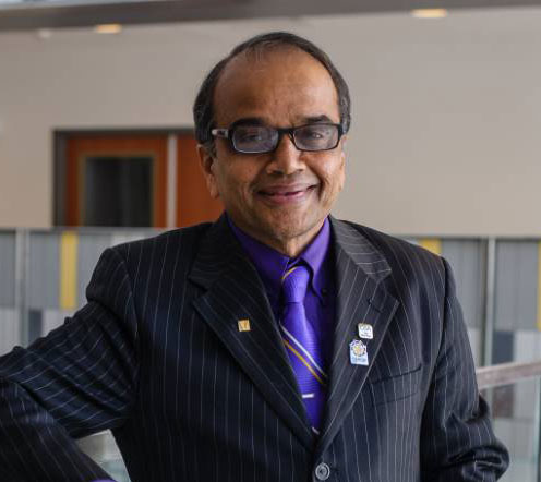 man in suit and tie, with glasses, smiling