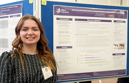 young woman standing in front of a poster, smiling