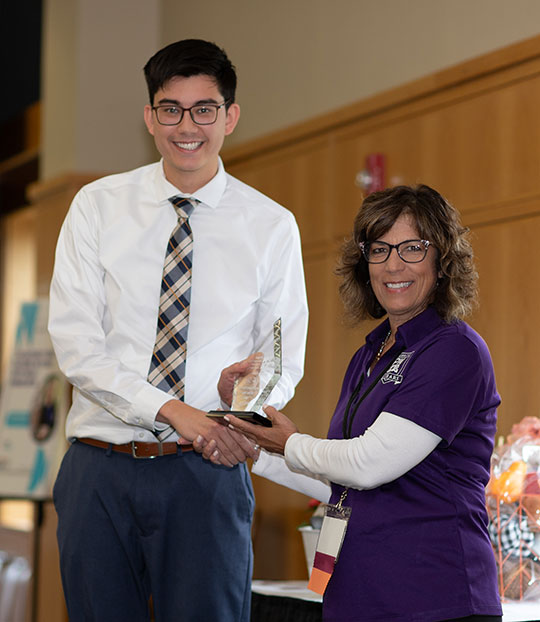 man receiving a trophy from a woman