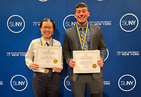photo of two people, a woman and a man, holding award certificates