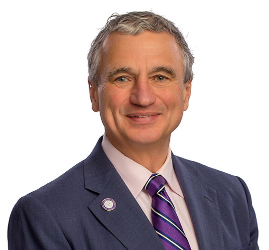 Alfred University's President, Mark Zupan wearing a navy sportscoat with a purple tie accented by white and black stripes