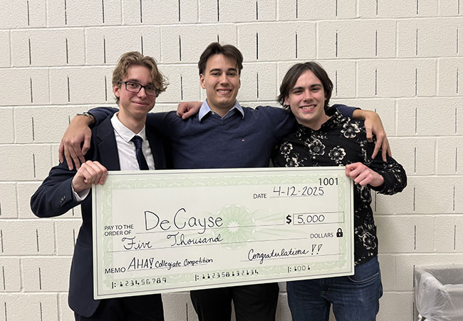 three young men standing in a row holding a large check