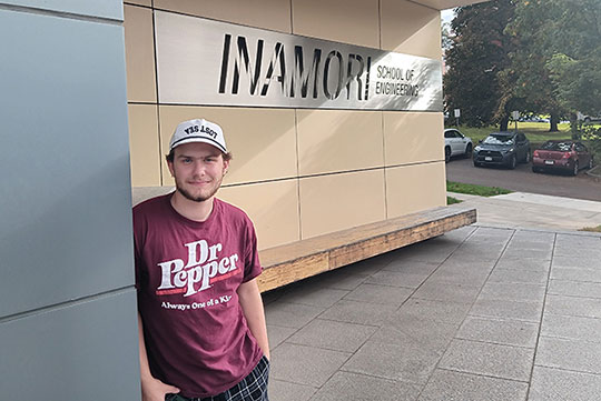 young man standing in front of a building/sign