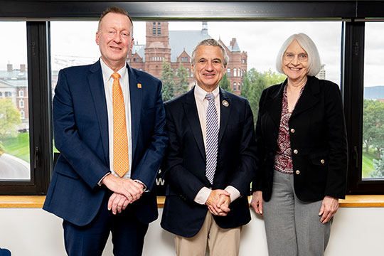 two men and a woman standing in a row, smiling