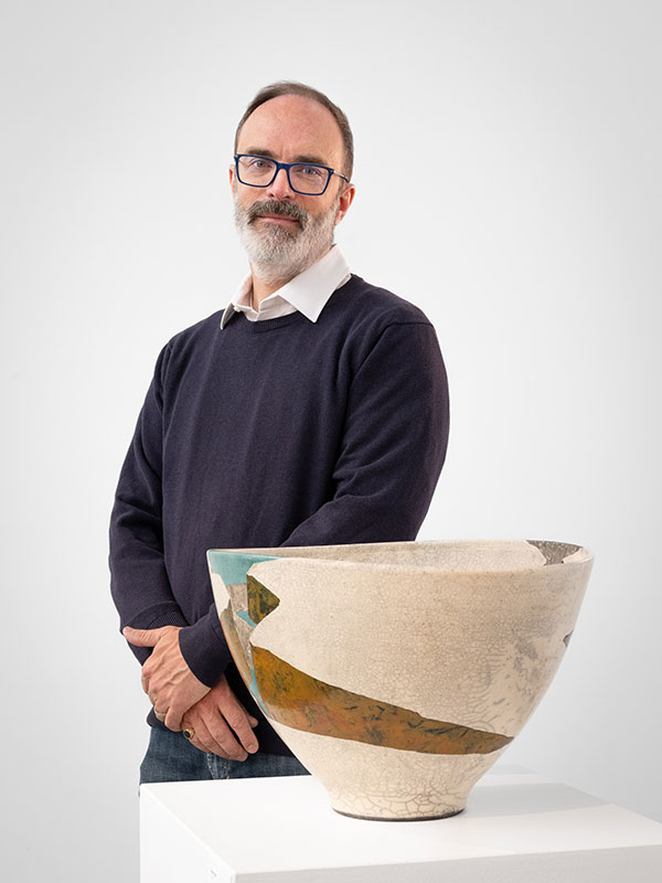 headshot of man wearing sweater, glasses