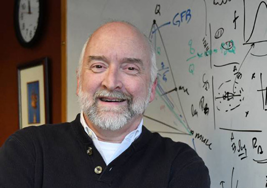 headshot of a man with a mustache and beard smiling