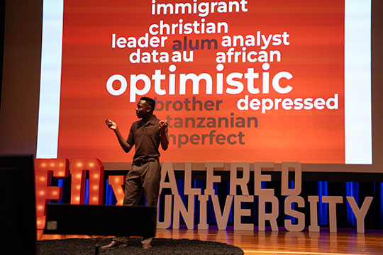 man talking into a microphone on stage