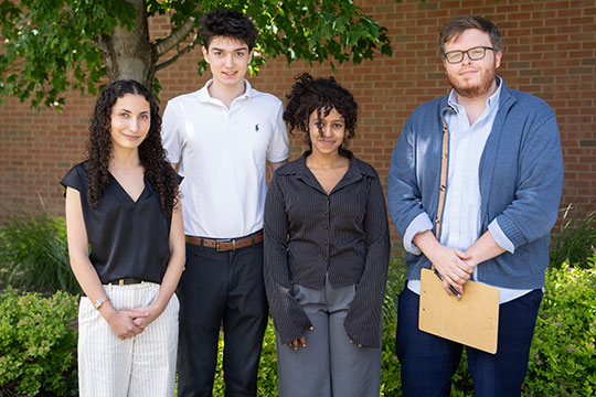 man standing next to three students