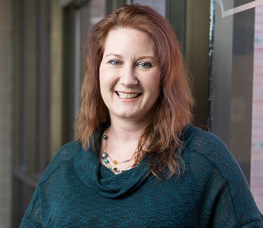 headshot of woman with long hair and a sweater, smiling