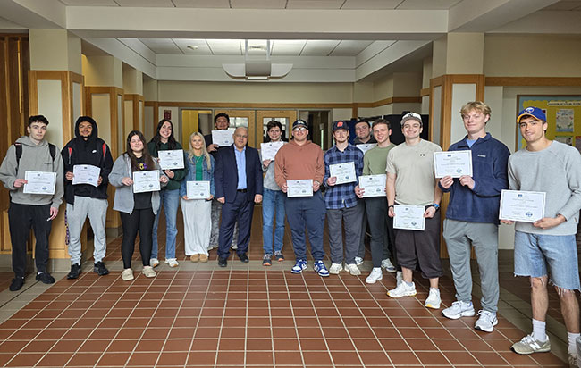 row of people standing in a row, holdin g certificates