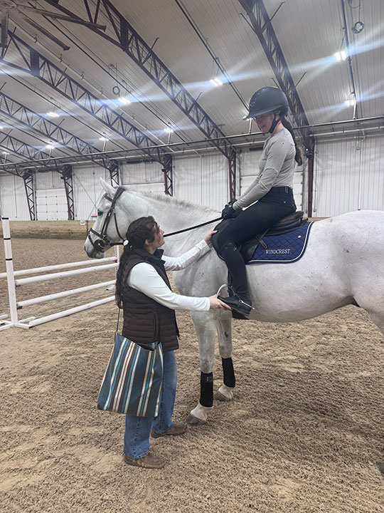 woman talking to another woman sitting on a horse