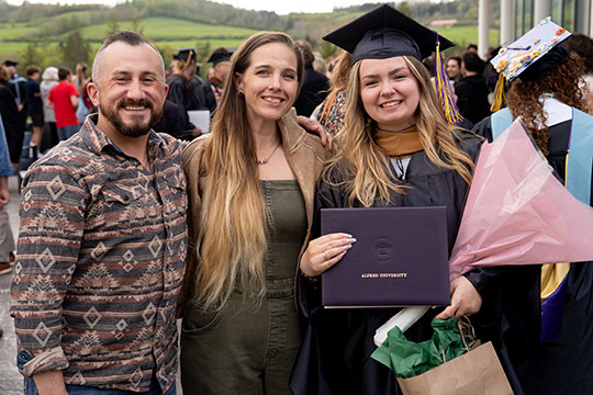 woman in cap and gown standing next toa man and woman