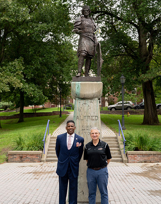 two people standing in front of a statue