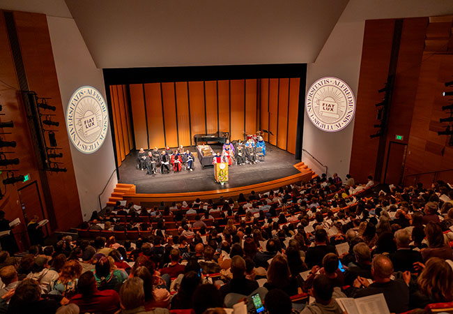 large crowd seated at theater in fron of stage