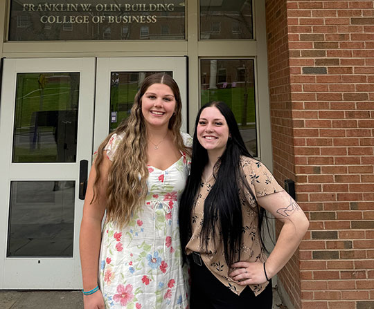 two young women standing in front of a building