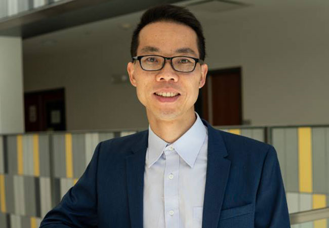 headshot of man in suit coat, wearing glasses