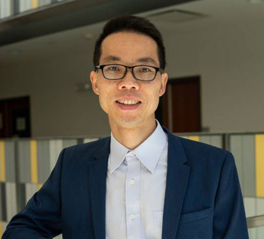 headshot of man wearing suit coat, glasses