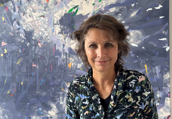 woman standing in front of a painting, smiling