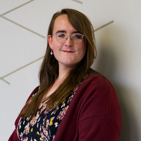 headshot of a person with long hair and glasses