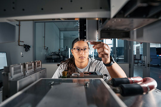 woman in white lab coat, working on lab equipment