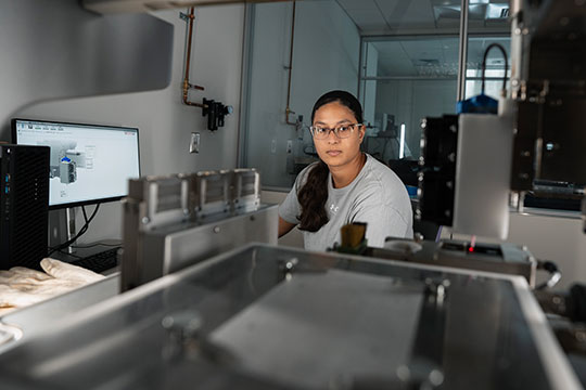 woman in white lab coat, working on lab equipment
