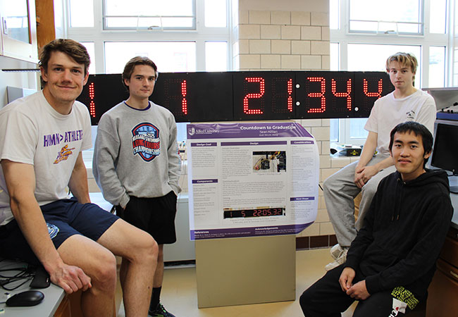 four people standing in front of a lighted digital clock
