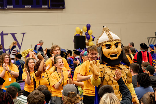 mascot leading a procession through a crowd