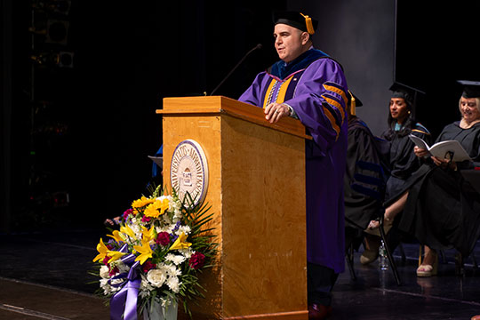 man in academic regalia at a podium