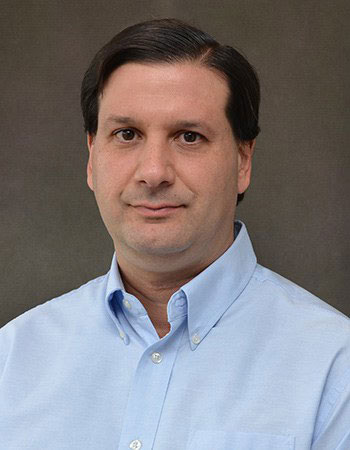 headshot of a man with light blue collared shirt and dark hair