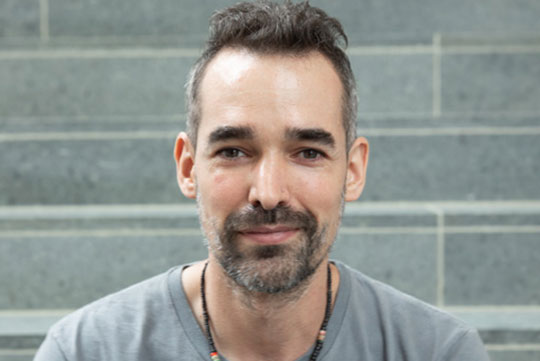 headshot of man with facial hair wearing t-shirt