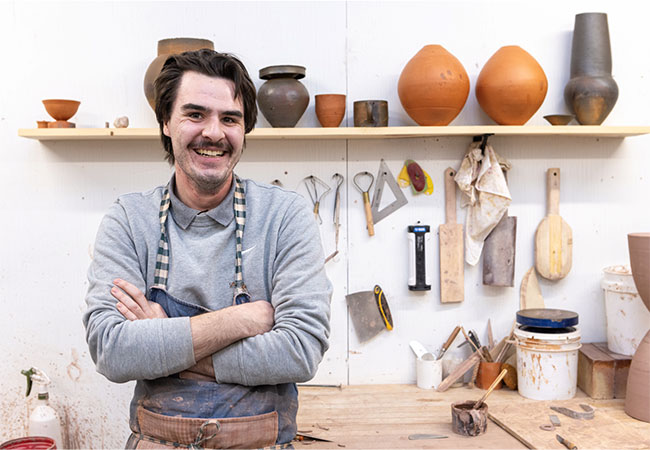 man standing in front of a bunch of clay pots