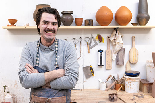 man standing in front of a bunch of clay pots