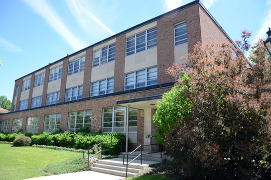 three story brick building with shrubs in front